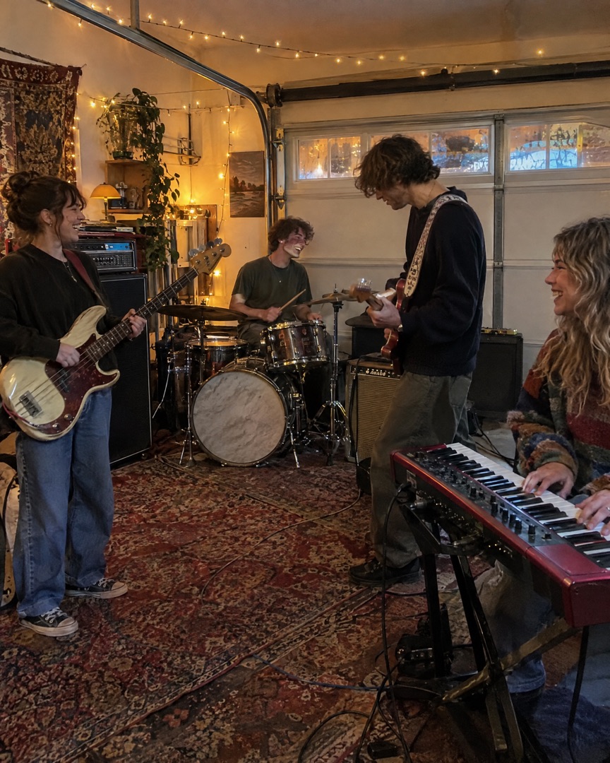 Four-piece band rehearsing in a garage with fairy lights